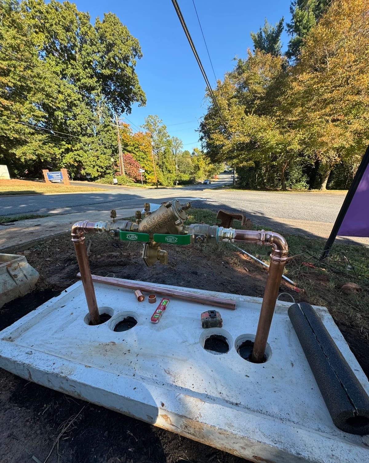 New copper backflow preventer assembly with MAX Plumbing service van in the background